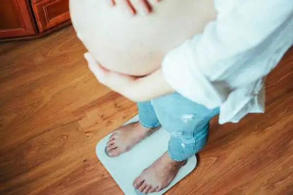 Image of woman weighing herself and experiencing weight gain through pregnancy Whitley Bay